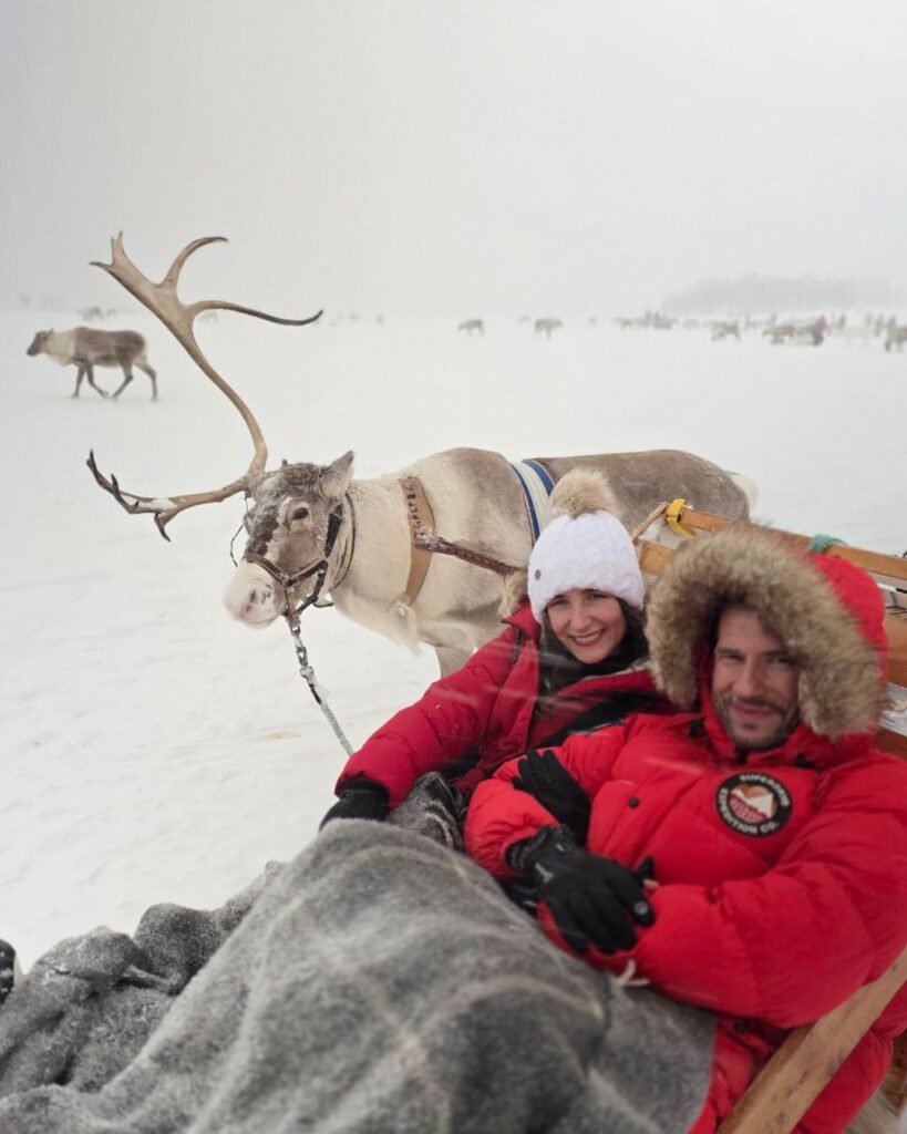 A picture after our sledding experience with reindeers close to Tromso with snow-covered surroundings and a reindeer in the background. 