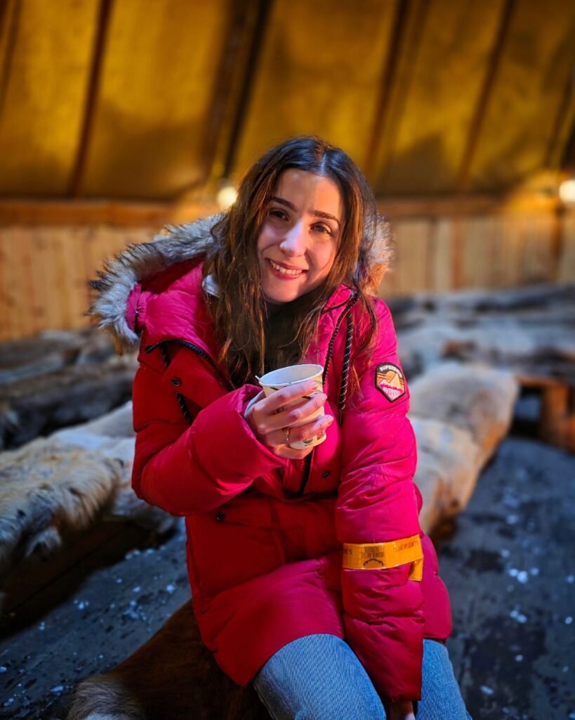 A Sami guide explaining traditional culture to tourists during a cultural session in Tromsø, in a typical Sami tent with hot drinks