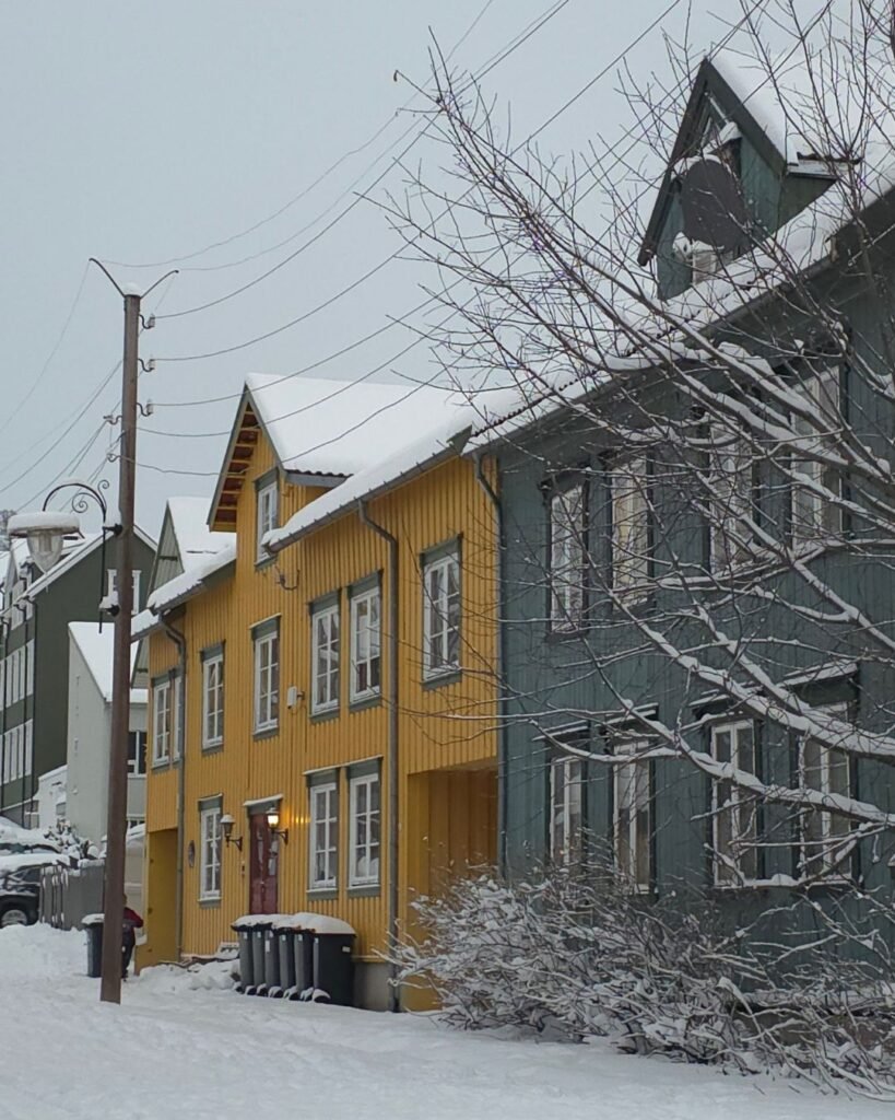 A scenic view of Tromsø city covered in snow, with colorful houses