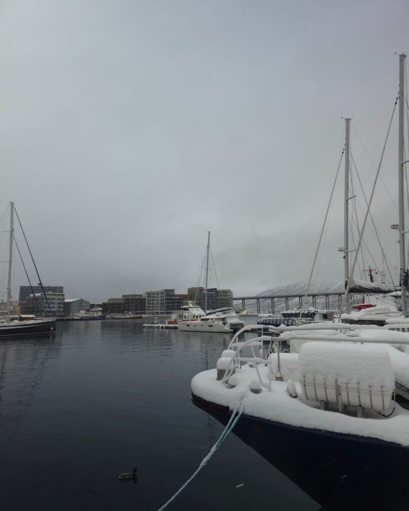 A scenic view with snowy boats at Tromsø Harbor.