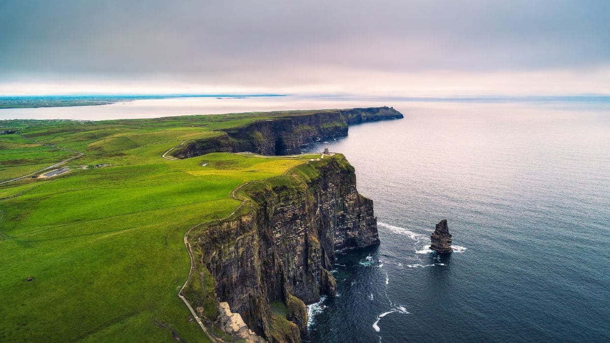 Panoramic view of the iconic Cliffs of Moher, showcasing the towering cliffs against the backdrop of the Atlantic Ocean on a clear day.