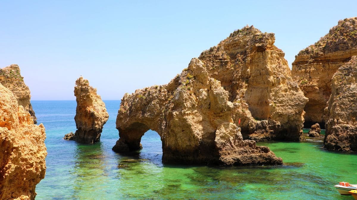 A stunning panoramic view of the Algarve coastline, featuring golden cliffs, turquoise waters, and picturesque beaches under a clear blue sky.