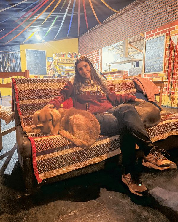 Ru with one of the dogs in the cosy dining area by the fireplace at Sky Dome Peru