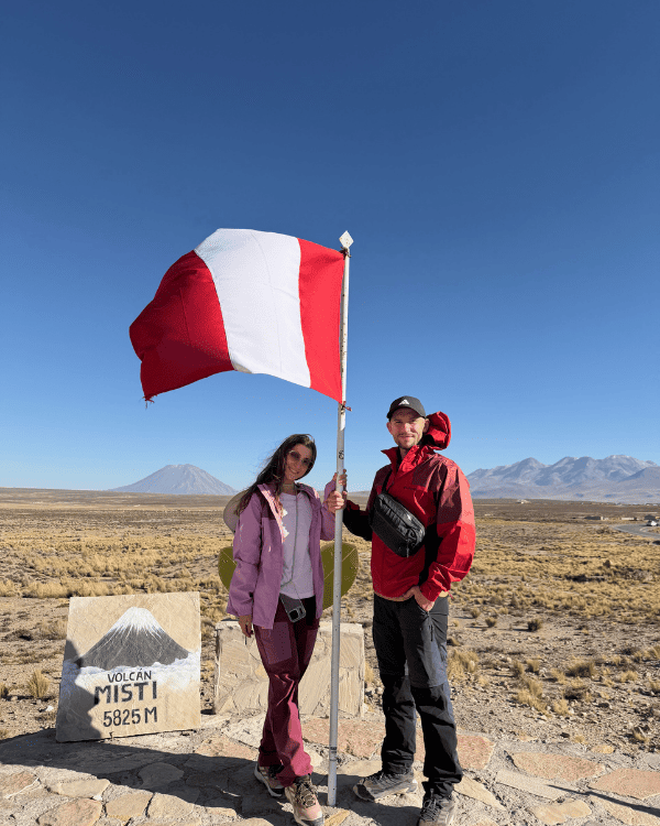 Colca Canyon Day Tour from Arequipa: Our Honest 2026 Review Colca Canyon day tour from Arequipa Peru Ru & Tiago with the Peruvian flag at a high Andean viewpoint on the Colca Canyon tour