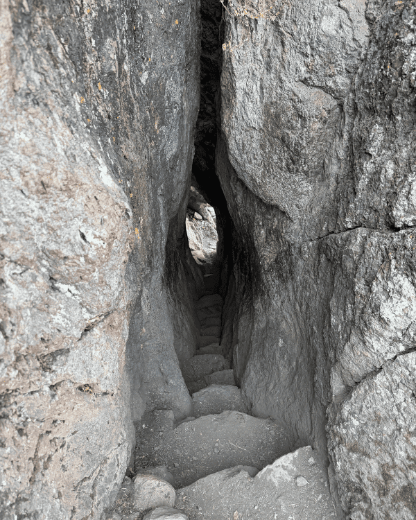Narrow rock tunnel with stone steps on the Pisac hiking trail