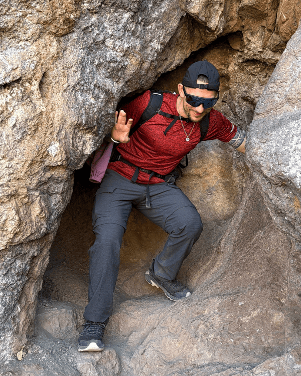 Hiker squeezing through a natural rock tunnel on the Pisac hiking trail
